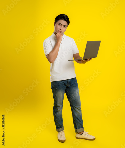 image of young businessman using laptop on yellow background