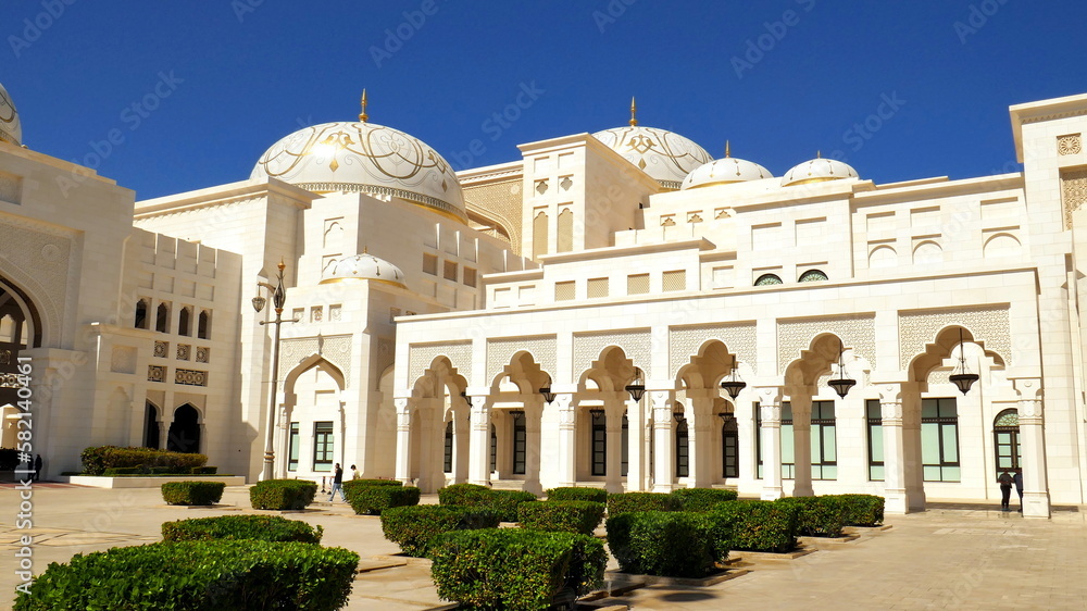 herrlicher Präsidentenpalast Qasr Al Watan in Abu Dhabi aus weißem Marmor mit Kuppeln und Hof mit grünen Büschen unter blauem Himmel 