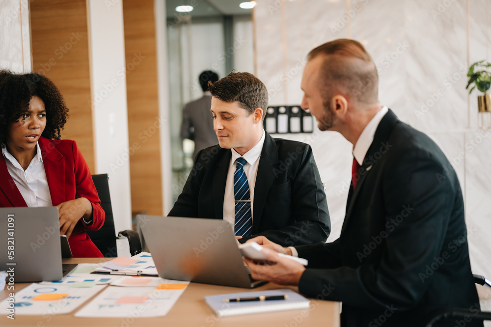 Happy businesspeople while collaborating on a new project in an office. Group of diverse businesspeople using a laptop and tablet in office.. Happy businesspeople while collaborating on a new project in an office. Group of diverse businesspeople using a laptop and tablet in office..