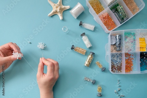 Fotografie Women's hands make summer beaded earrings