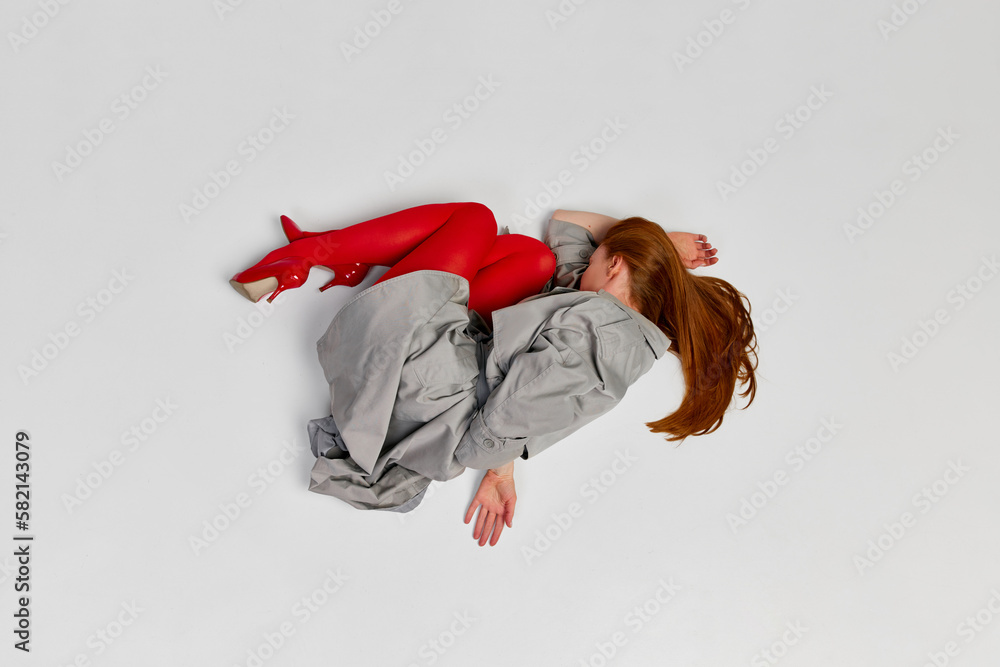 Impersonal human emotions. Stylish girl in grey coat and bright red tights moves over light background. Expressive fashion. Concept of art photography, beauty