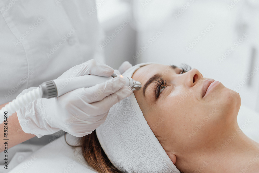 Radiofrequency facial skin lifting. Hardware cosmetology RF lifting procedure and hardware facial massage. Rejuvenation, skin care in a beauty salon. Woman doctor cosmetologist and girl in spa clinic. Radiofrequency facial skin lifting. Hardware cosmetology RF lifting procedure and hardware facial massage. Rejuvenation, skin care in a beauty salon. Woman doctor cosmetologist and girl in spa clinic.