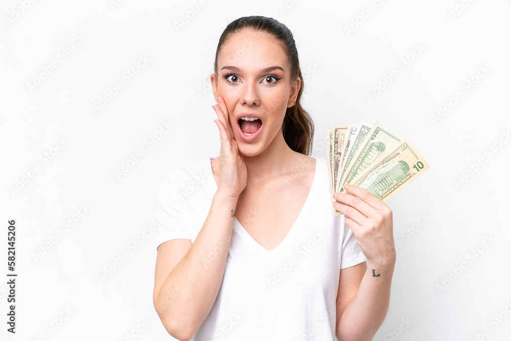Young caucasian woman taking a lot of money isolated on white background with surprise and shocked facial expression Young caucasian woman taking a lot of money isolated on white background with surprise and shocked facial expression