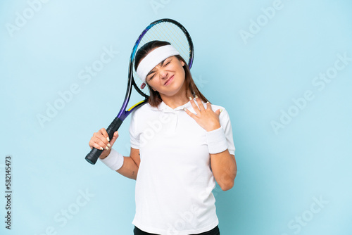 Young tennis player woman isolated on blue background suffering from pain in shoulder for having made an effort © luismolinero