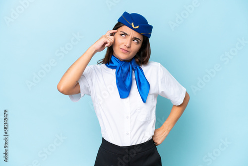 Airplane stewardess caucasian woman isolated on blue background having doubts and with confuse face expression