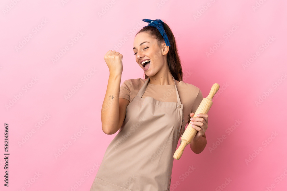 Young woman holding a rolling pin celebrating a victory Young woman holding a rolling pin celebrating a victory
