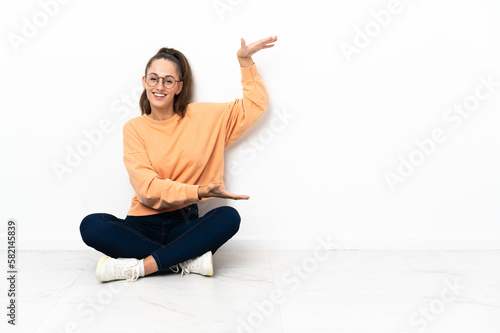 Young woman sitting on the floor holding copyspace to insert an ad