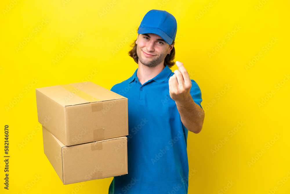 Delivery handsome man isolated on yellow background making money gesture Delivery handsome man isolated on yellow background making money gesture