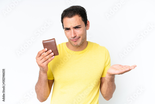 Young caucasian man holding a wallet isolated on white background making doubts gesture while lifting the shoulders