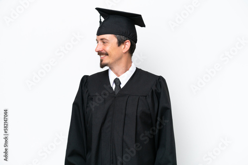 Young university graduate man isolated on white background looking side