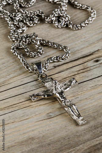 Close up of silver Crucific necklace isolated on wooden background photo