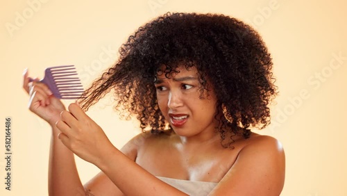 Hair, comb or tangled and an afro woman in studio on a yellow background struggling with haircare. Beauty, salon or hairstyle and an unhappy woman at the hairdresser with curly frizz or knots