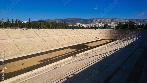 Athens, Greece - 03.29.2018: A side view of the interior of the Panathenaic Stadium, Kallimarmaro, on a sunny day under a blue sky and sunlight, with shadows and tourists walking
