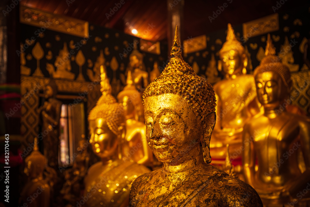 Fototapeta premium Golden group buddha faces statue meditation sitting with a Golden Buddha background up down and sitdown.