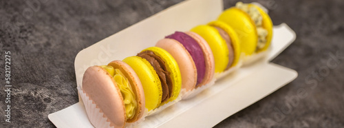 five macaroons in paper packaging on the table. packaging process. home bakery concept.