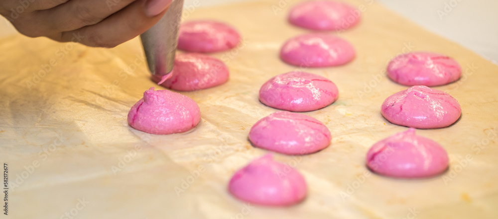 the confectioner squeezes out drops of pink macarons dough. close-up. home bakery concept. the confectioner squeezes out drops of pink macarons dough. close-up. home bakery concept.