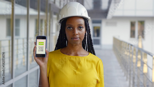 African-American woman architect showing vaccinated qr-code on smartphone at camera photo