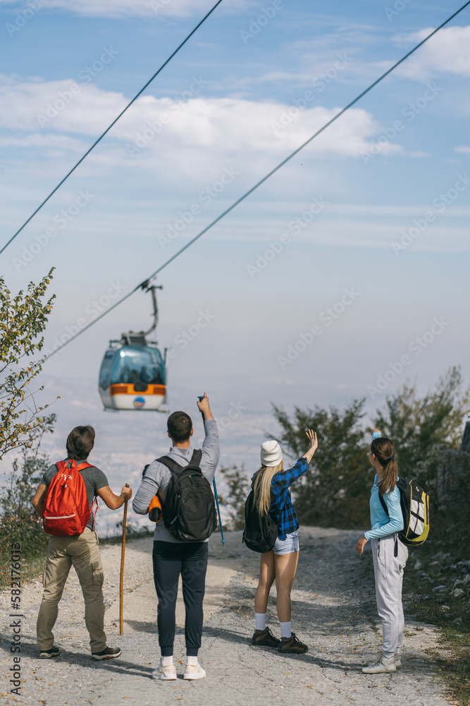 Obraz premium Four hikers looking at the zip line on top of the mountain