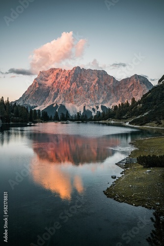 Vertical shot of a lake surrounded by rocky hills during the sunset in Austria © Dominik Ebner/Wirestock Creators