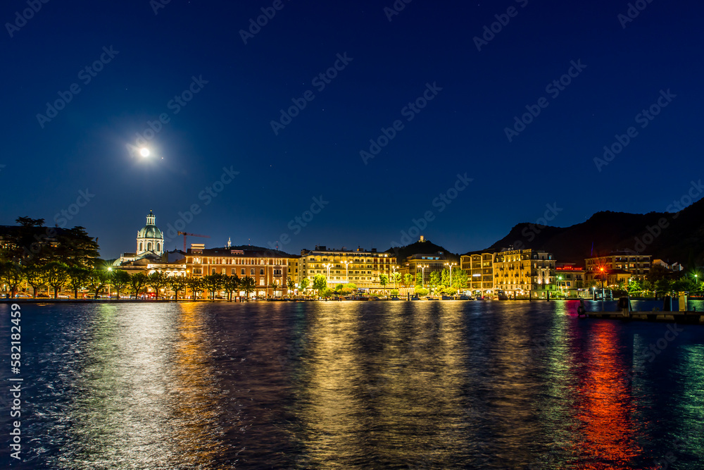 The city of Como, photographed in the evening, with the lakefront, the cathedral, and the surrounding mountains.
