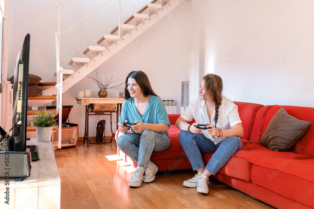 Young women playing video games in living room Young women playing video games in living room