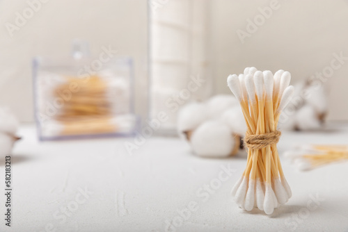 Cotton buds on a light concrete background.Eco-friendly materials. Wooden, cotton swabs on a white background.Bamboo swabs and cotton flowers.Zero waste, plastic free lifestyle concept.Place for text.