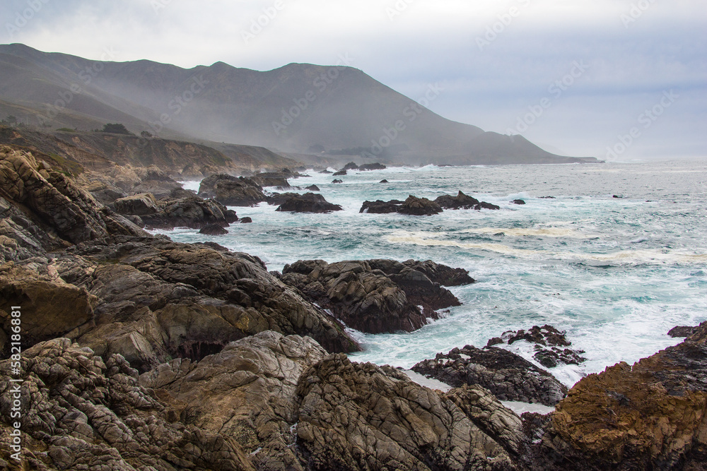 The rocky California coastline as off the Pacific Coast Highway near the Big Sur area. Classic foggy conditions and rough waters.