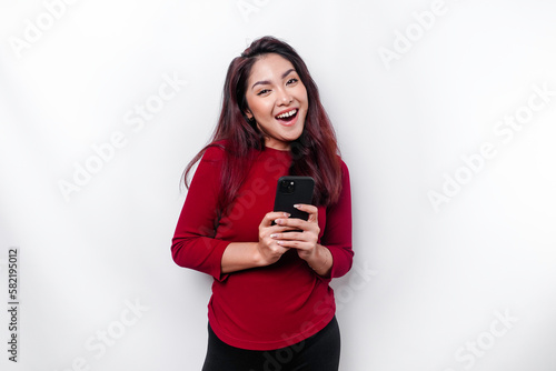 A portrait of a happy Asian woman dressed in red and holding her phone, isolated by white background