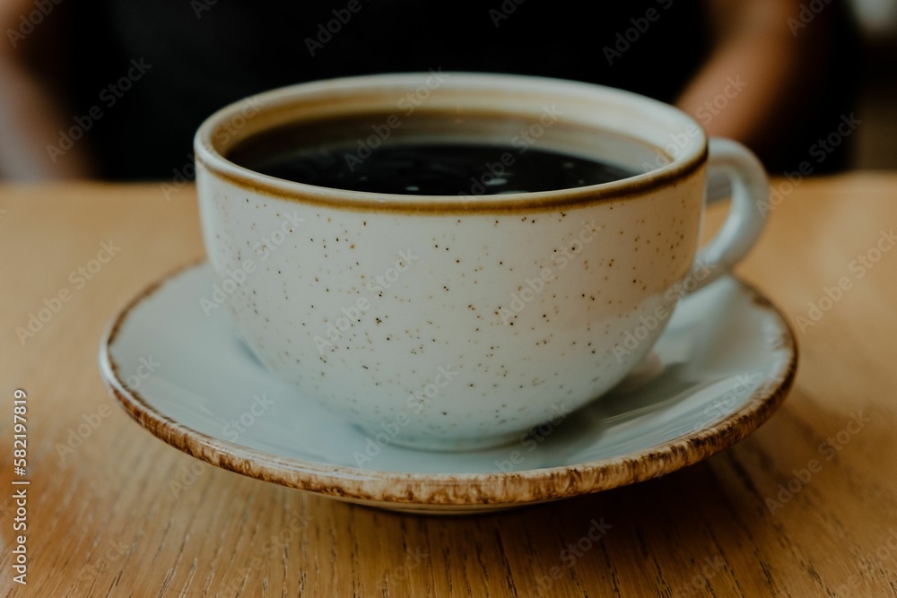 White ceramic coffee cup with a saucer on a wooden table, ready to be served White ceramic coffee cup with a saucer on a wooden table, ready to be served