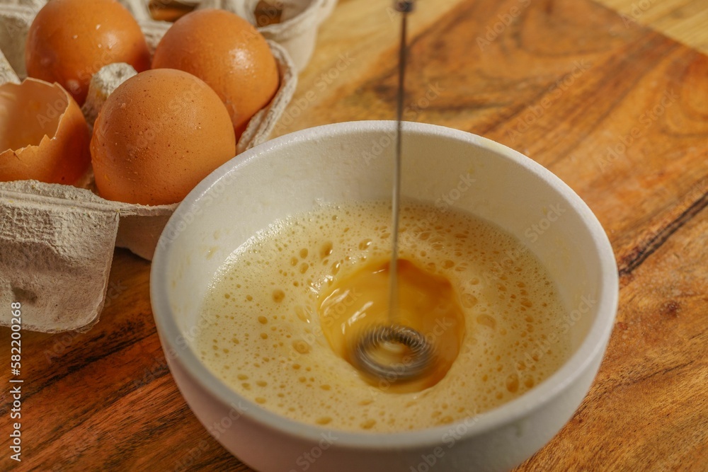 beating one egg in a bowl with a mixer with an egg cup at the bottom