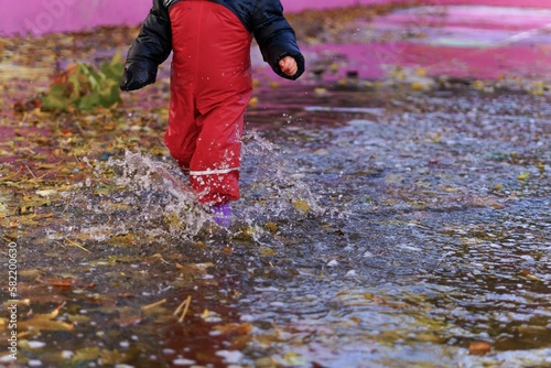 child splashing water in a puddle on a rainy day