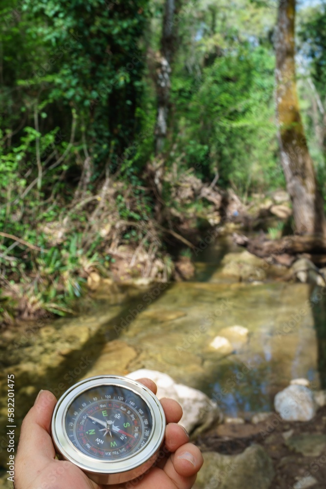 Naklejka premium man orienting himself with a compass in the river