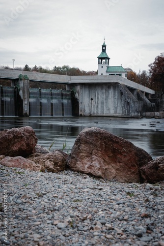 Vertical shot of the Hochablass seen from the rocky shore under the cloudy sky in Augsburg, Germany photo