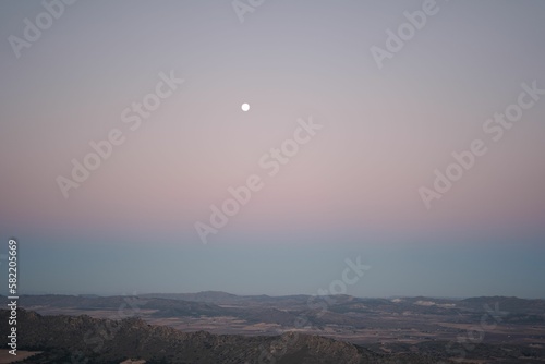 Beautiful white moon in a sunset sky over rural fields