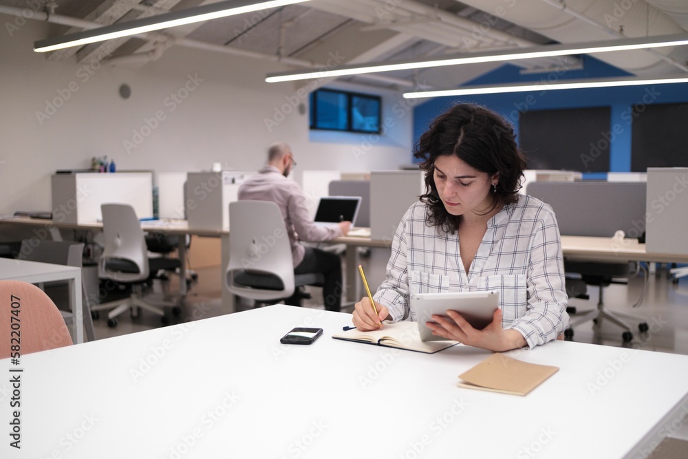 Caucasian female working in an office holding a laptop