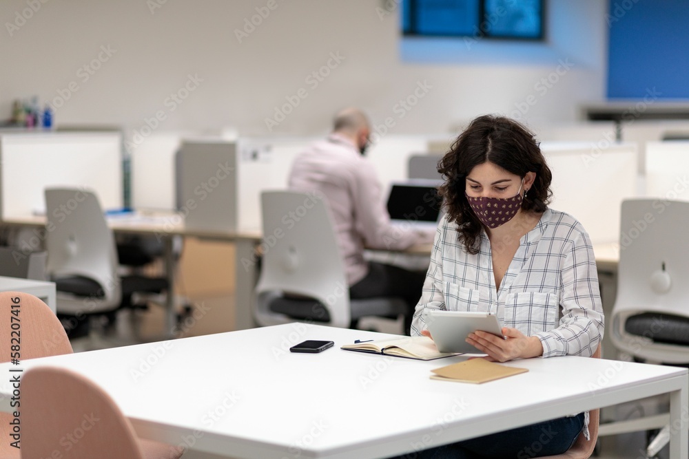 Caucasian female wearing a face mask working in an office Caucasian female wearing a face mask working in an office