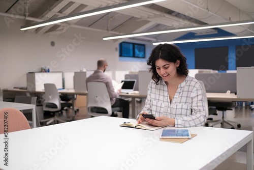 Caucasian female working in an office holding a phone and smiling