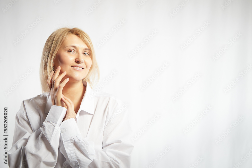 Portrait of a pretty calm sweet blonde smiling woman posing on a white background. Happy girl model in white shirt in studio. Copy space Portrait of a pretty calm sweet blonde smiling woman posing on a white background. Happy girl model in white shirt in studio. Copy space