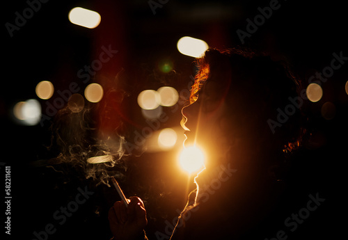 Silhouette of young woman smoking cigarette