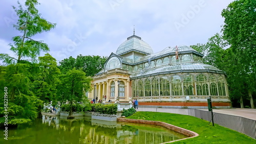 Palacio de Cristal del Retiro, Madrid, Spain - May 28, 2018: Crystal Palace with glass structure surrounded by trees and pond in Buen Retiro Park