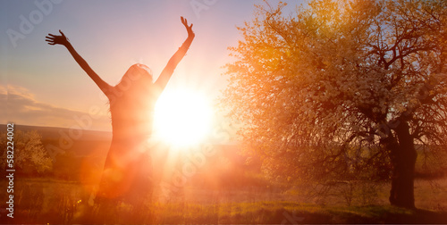 Glückliche Frau unter einem blühenden Apfelbaum im Gegenlicht