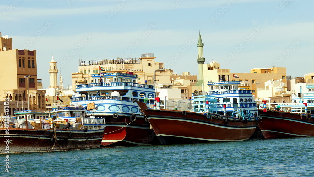 malerische Schiffe auf dem Meeresarm Creek in der Altstadt von Dubai vor alten Häusern und Moschee