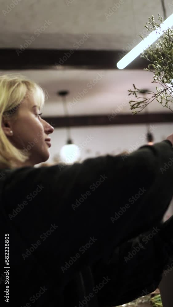 Awesome florist girl working in flower shop, preparing flowers for sale, vertical video Awesome florist girl working in flower shop, preparing flowers for sale, vertical video