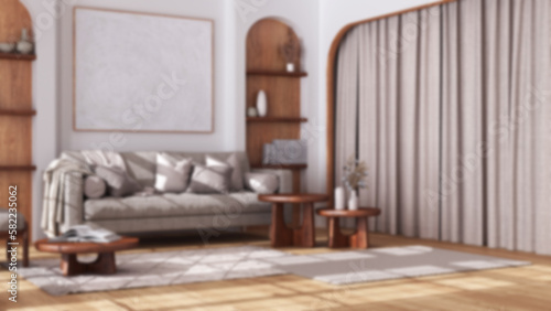 Blurred background  wooden living room in boho style with arched door and parquet floor. Fabric sofa  carpet  shelves and table. Bohemian interior design