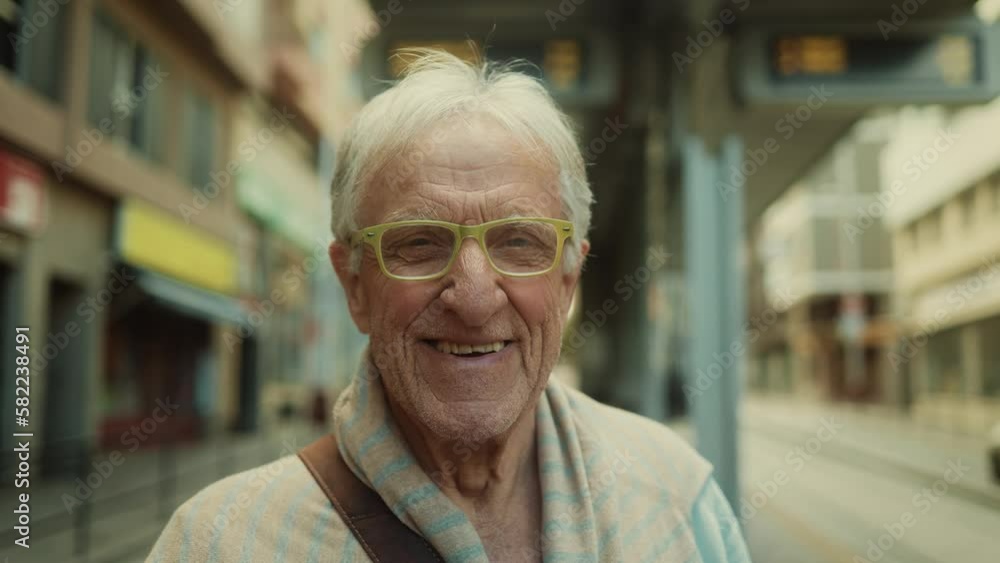 Happy senior man smiling in front of camera while waiting at tram station in the city Happy senior man smiling in front of camera while waiting at tram station in the city