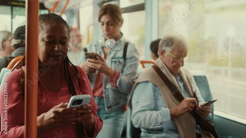 Multiracial people using mobile smartphone while traveling by public bus