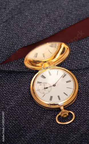 Golden pocket watch on the background of a man's suit. Retro style and vintage fashion. 