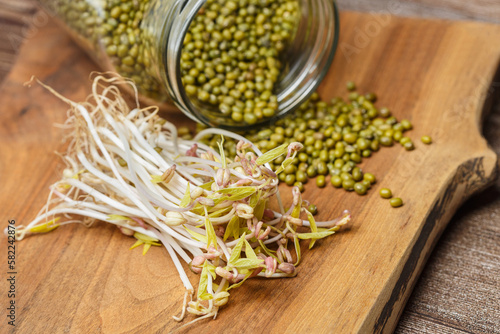 Sprouted mung beans and green mung beans in a glass jar on a wooden background