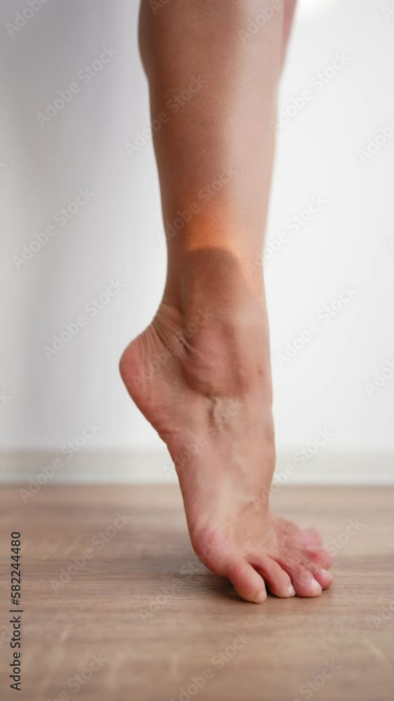 Vertical Video, Beautiful Slim Female Legs Stand on the Parquet Floor on Background of a White Wall and Move Gracefully Barefoot. Concept of Care for the Woman Body and Feet. Slow Motion, Close-up. Vertical Video, Beautiful Slim Female Legs Stand on the Parquet Floor on Background of a White Wall and Move Gracefully Barefoot. Concept of Care for the Woman Body and Feet. Slow Motion, Close-up.
