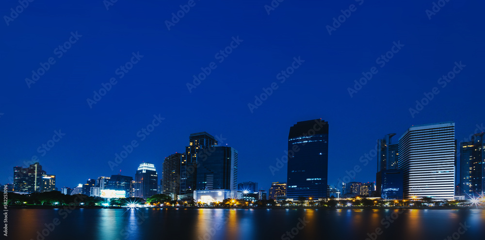 Night view of skyscrapers with river in business district of the capital city in Bangkok, Thailand. with copy space and text design for business